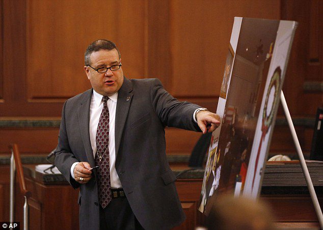 A man in suit and tie pointing to an image.